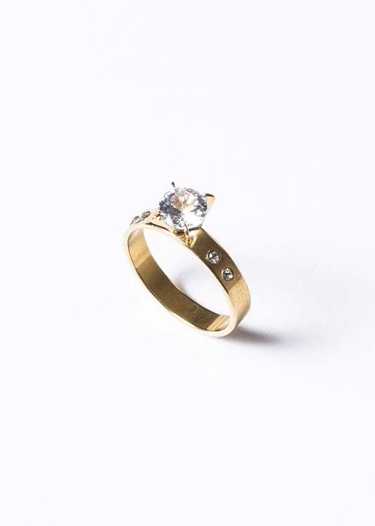 Anillo cintillo piedra al centro y laterales acero quirúrgico dorado